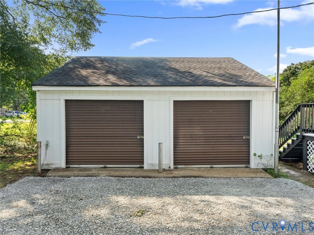 4818 Castlewood Road, Richmond, VA 23234 Spacious two-bay garage with brown roll-up doors, white exterior siding, and a pitched roof