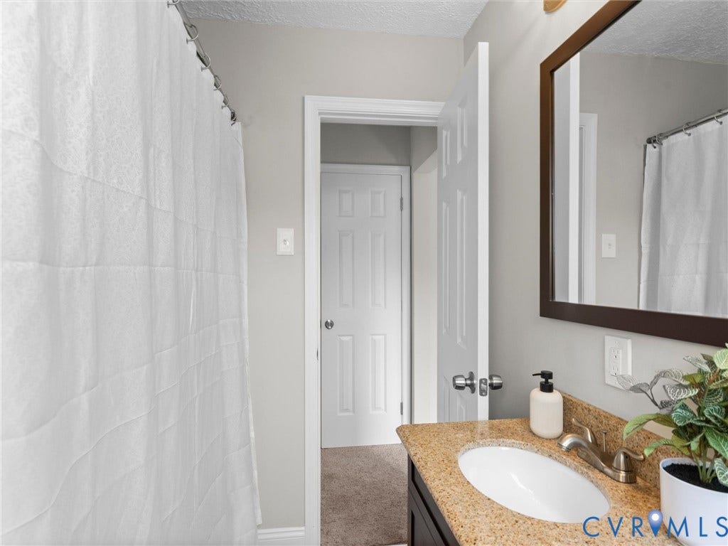 4818 Castlewood Road, Richmond, VA 23234 Bathroom with a dark wood-finish vanity, granite-style countertop, and an undermount sink