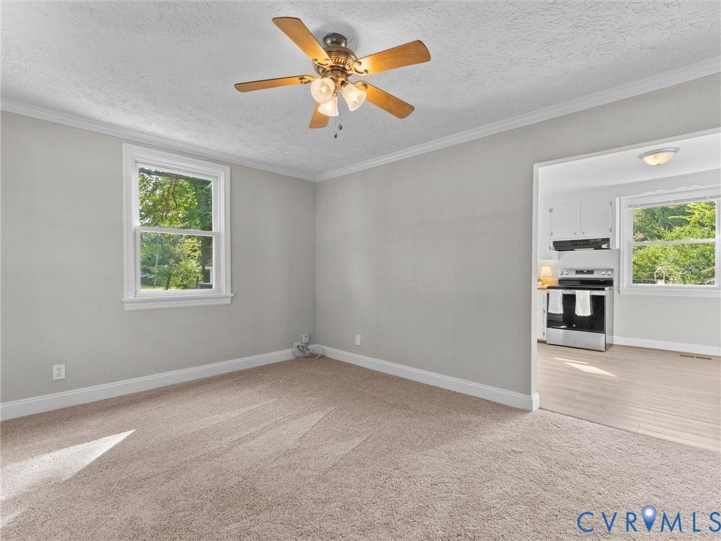 4818 Castlewood Road, Richmond, VA 23234 Bright, open living space featuring neutral gray walls, gleaming wood-finish flooring, and abundant natural light from dual windows