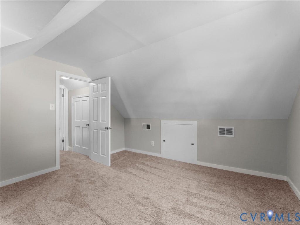 4818 Castlewood Road, Richmond, VA 23234 Spacious attic room with vaulted ceilings, abundant natural light from multiple windows, and warm wood-finish flooring