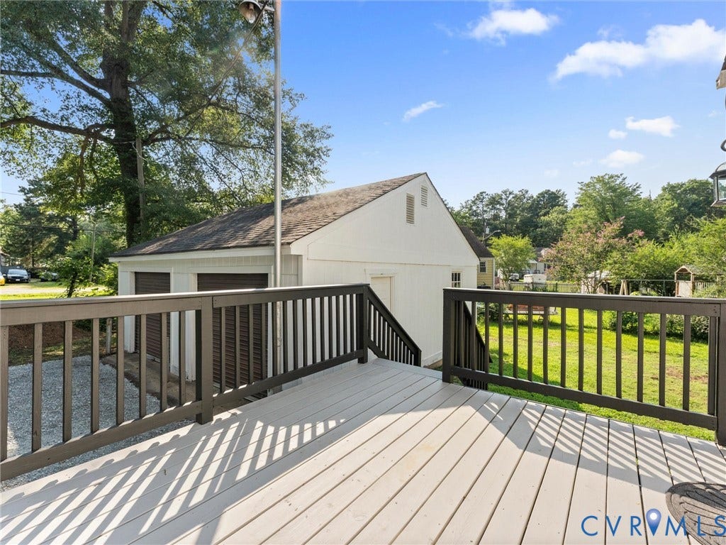 4818 Castlewood Road, Richmond, VA 23234 Expansive composite deck featuring light-finish decking with black aluminum railings and balusters, overlooking manicured lawn bordered by mature trees