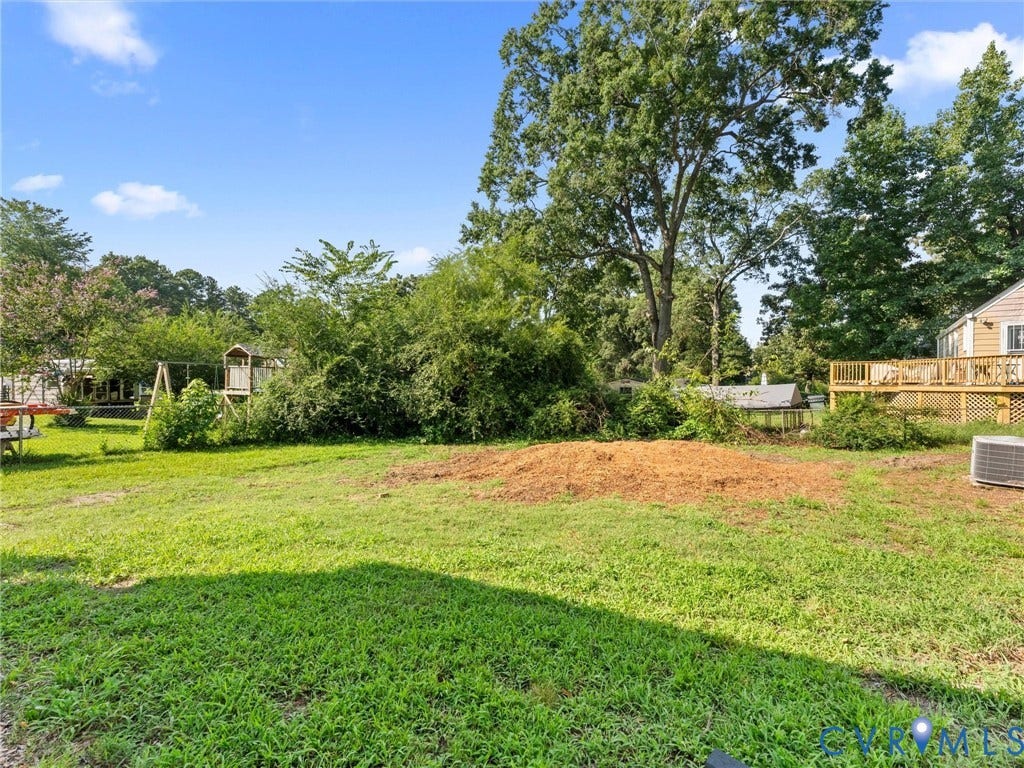 4818 Castlewood Road, Richmond, VA 23234 Expansive green lawn with mature trees and a raised outdoor deck