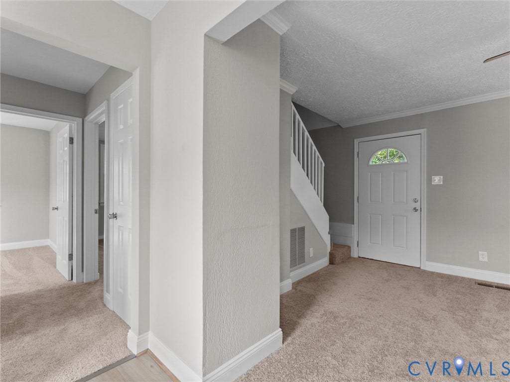 4818 Castlewood Road, Richmond, VA 23234 Spacious upper-level landing featuring neutral carpeting, white six-panel doors, and abundant natural light from a transom window