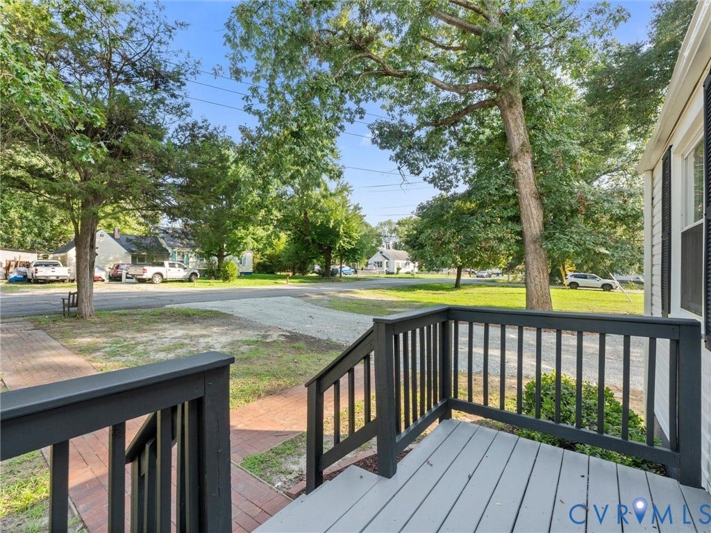 4818 Castlewood Road, Richmond, VA 23234 Spacious composite deck with black aluminum railings and gray composite decking, overlooking a mature tree-lined yard with established landscaping and brick hardscape