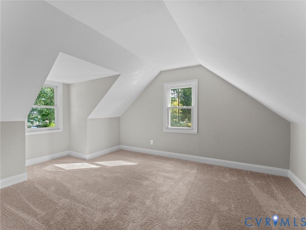 4818 Castlewood Road, Richmond, VA 23234 Bright attic bedroom with vaulted ceilings, dual windows flooding the space with natural light, and neutral wall finishes