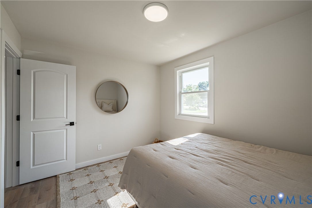 Wood-finish flooring, white paneled door with dark hardware, recessed lighting, and a window with white trim