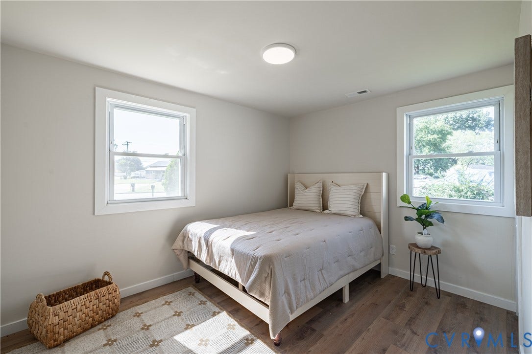 Recessed ceiling lighting, two windows with white trim, light tone wall paint, wood-finish flooring, and white baseboards