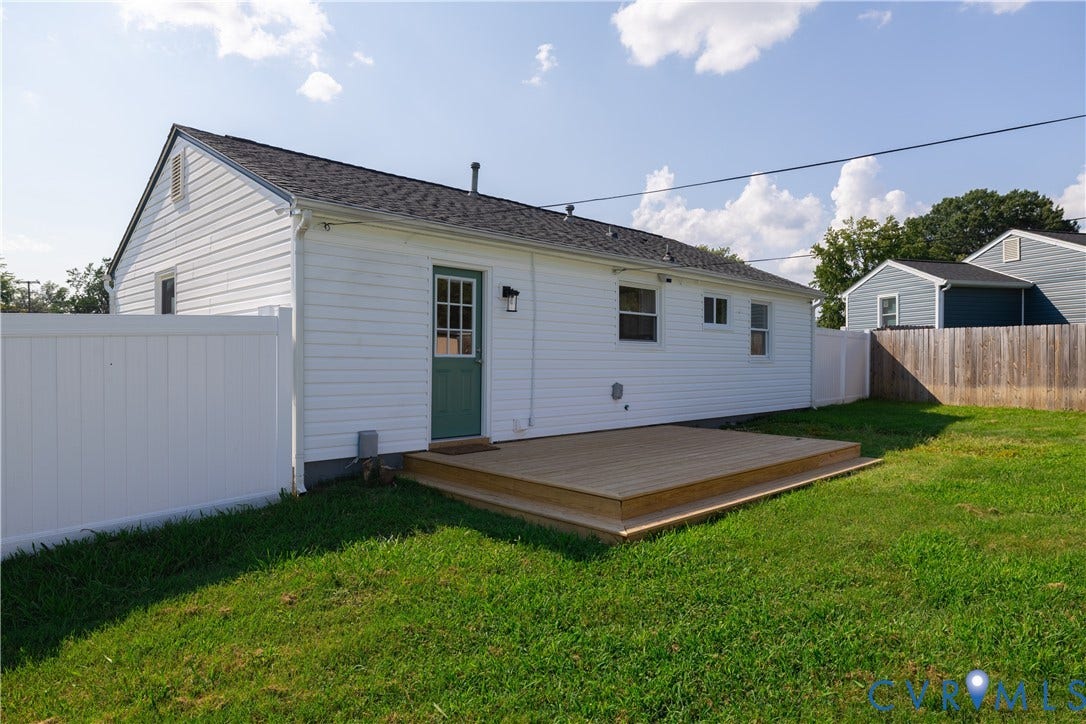 Exterior featuring white siding, a dark shingle roof, and a green paneled door with an exterior light fixture