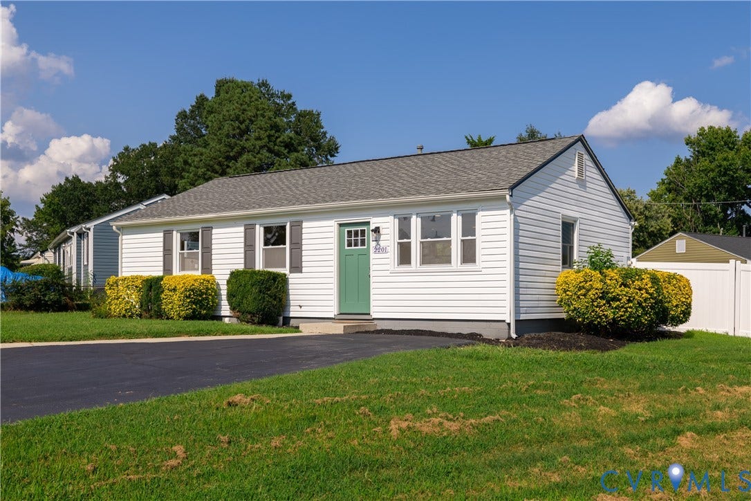White siding exterior with a charcoal shingle roof, a green entry door, and dark gray window shutters
