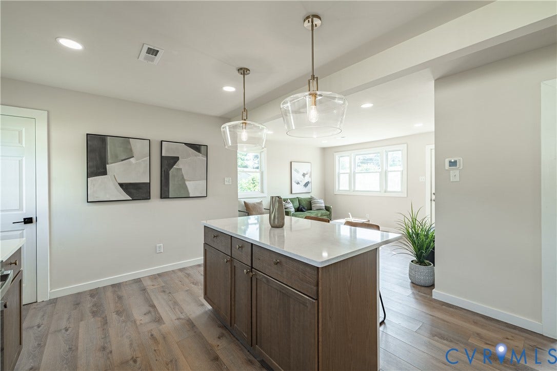 Kitchen island with a light-toned countertop, wood-finish cabinetry, and two pendant lights