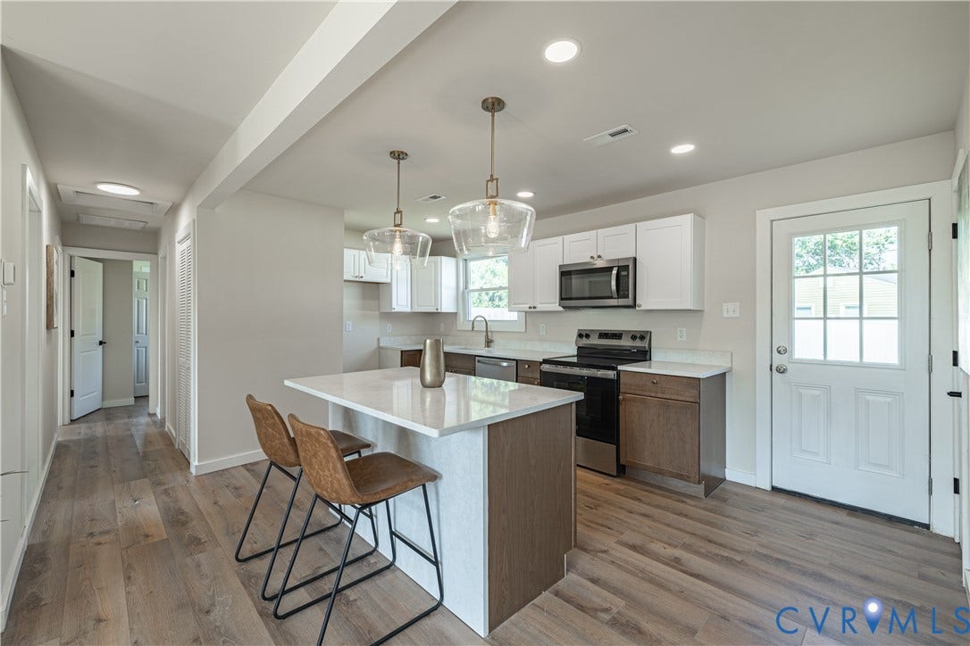 Kitchen featuring a central island with countertop seating, stainless steel appliances, recessed lighting, and wood-finish flooring