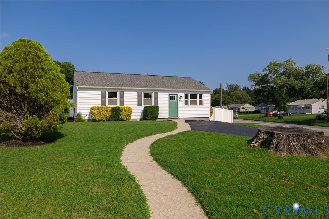 White siding exterior with gray shutters, asphalt shingle roof, paved driveway, and a concrete pathway