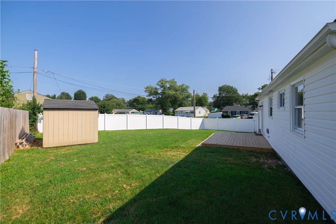 Expansive backyard with a manicured lawn, wood privacy fencing, a storage shed, and a wood deck