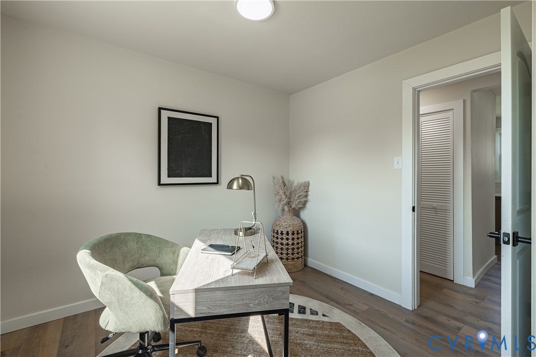 Dedicated home office featuring warm wood-finish flooring, soft neutral wall finishes, and abundant natural light from a recessed ceiling fixture