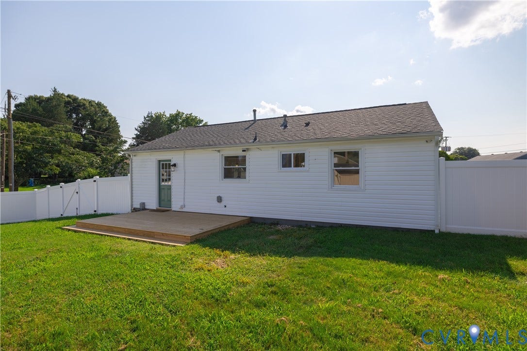 Private rear yard with wood deck, white vinyl fencing, and white siding exterior