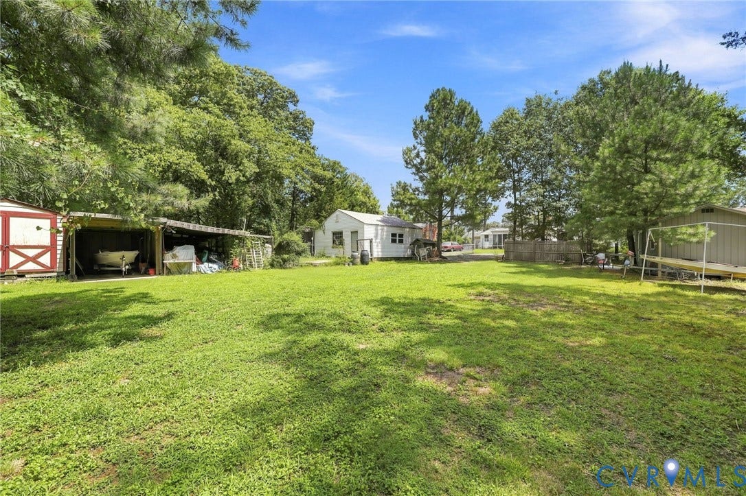 1904 Fon Du Lac Road, Henrico, VA 23229 Expansive grassy area with mature trees, red and white shed, covered storage structure, and an additional storage building