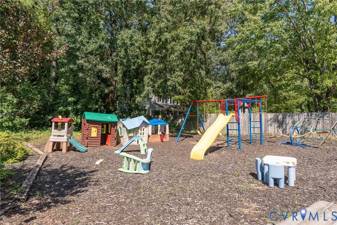 Expansive backyard with a wood chip ground cover, mature trees, and a privacy fence