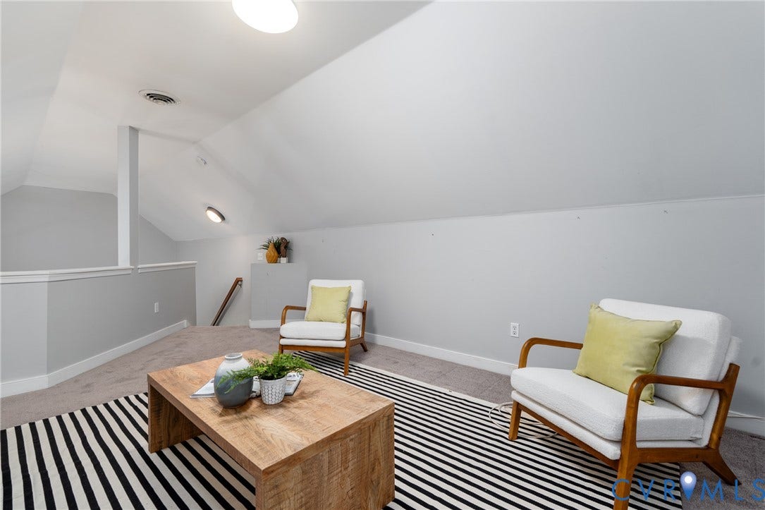 Sloped ceilings, overhead lighting, carpeted flooring, and a half-wall partition