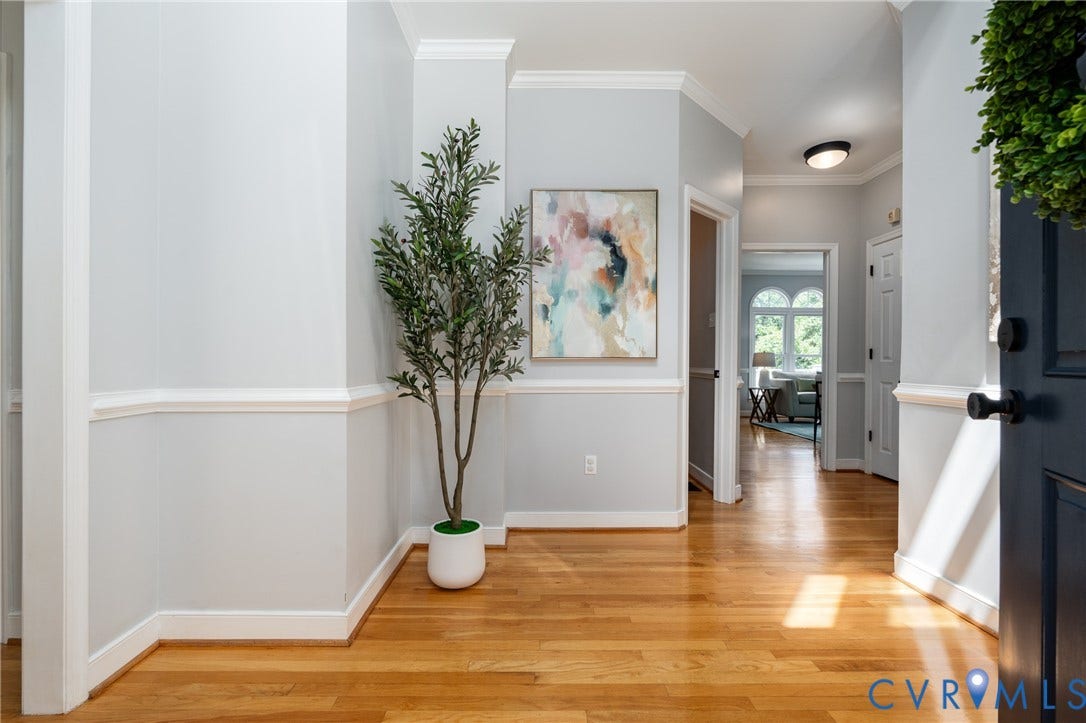Hardwood flooring throughout, crown molding, chair rail detailing, recessed lighting, and a paneled interior door