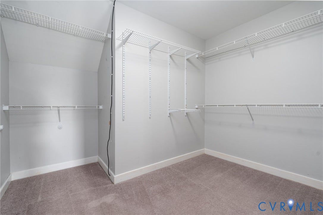 Walk-in closet featuring wire shelving, built-in storage, light gray walls, white baseboards, and gray carpet