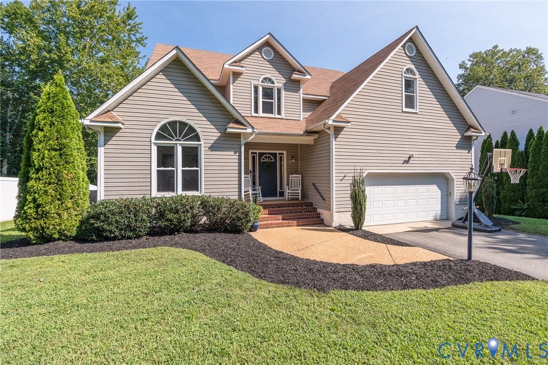Two-story Colonial with vinyl siding, brick front entry, and brick chimney detail