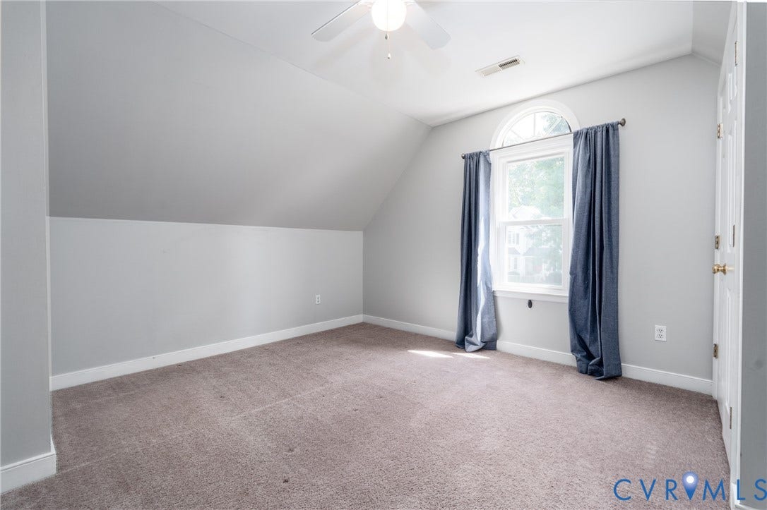 Vaulted ceiling with an integrated ceiling fan, arched window with white trim, and light gray wall paint