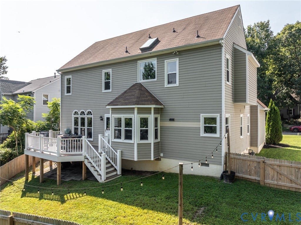 Classic Colonial-style home featuring gray vinyl siding, a pitched roof with multiple dormers, and a covered front entry with arched transom windows