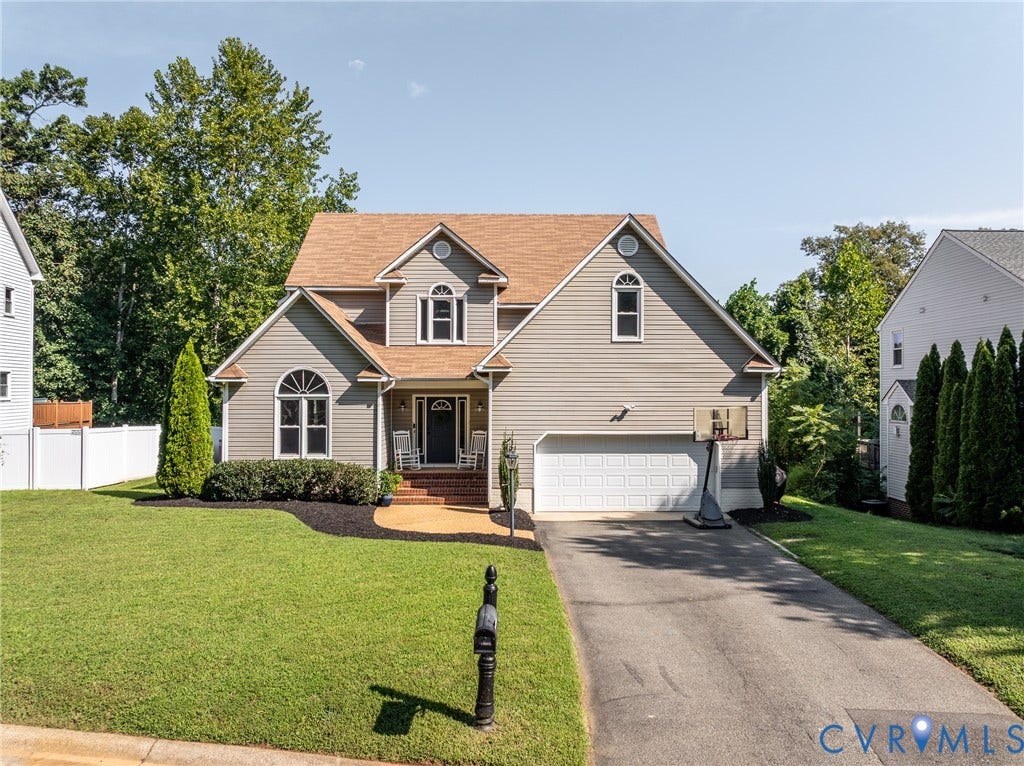 Two-story Colonial with stucco and siding exterior, featuring a peaked roofline with dual gables and composite shingle roof