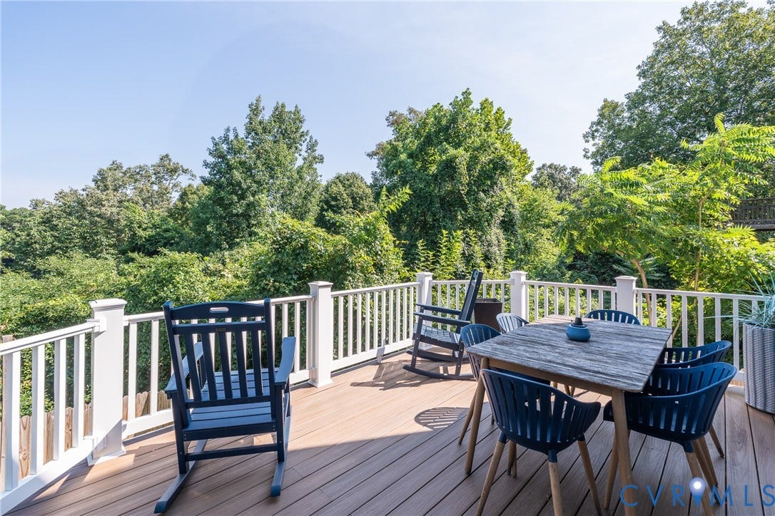 Spacious outdoor deck featuring composite decking, white balustrade railing, and mature tree landscaping