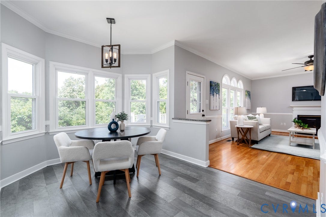 Bay window dining area with wood-finish flooring, a contemporary chandelier, and a partial wall with a granite-style countertop
