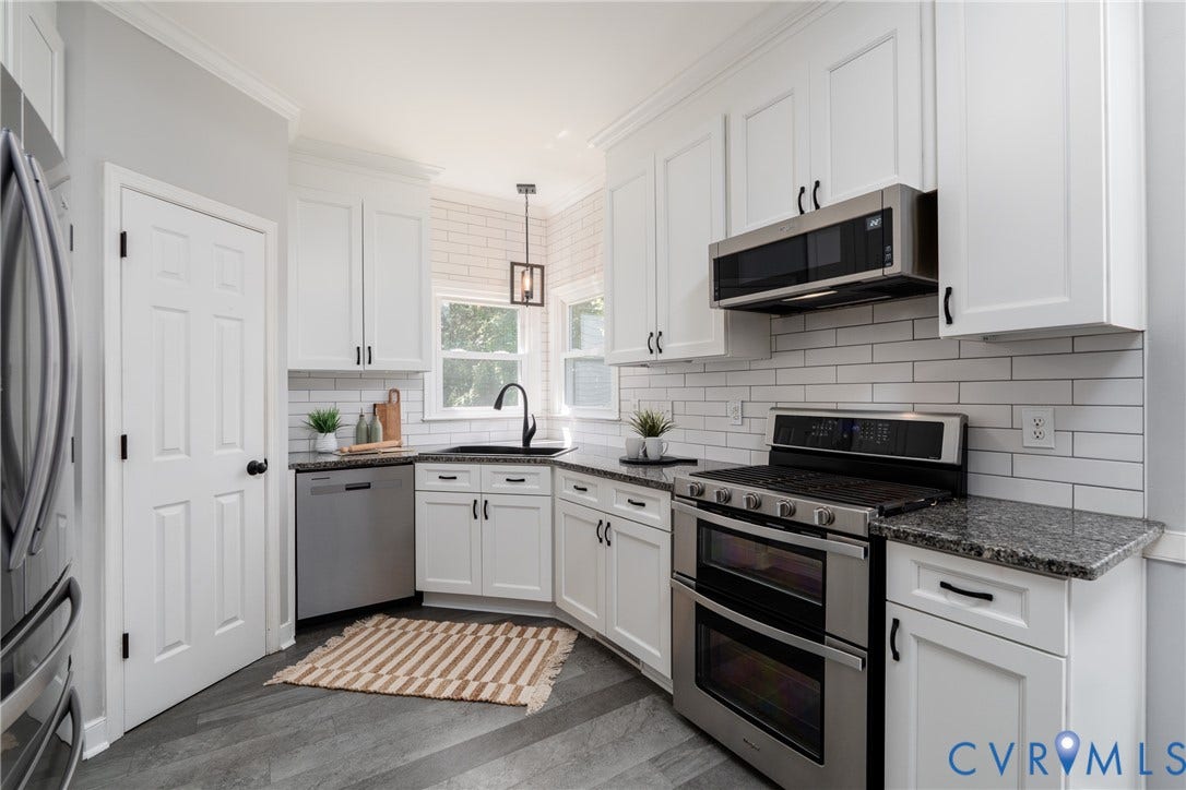 White shaker cabinetry, dark granite countertops, stainless steel appliances, subway tile backsplash, and wood-finish flooring