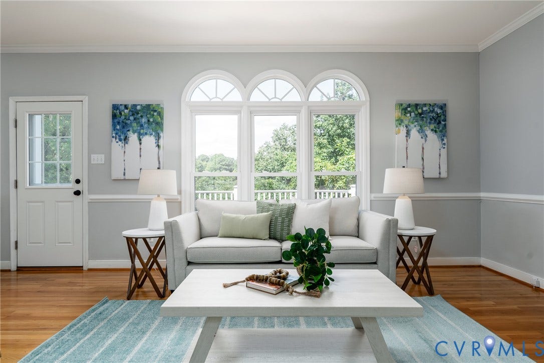 Hardwood flooring, crown molding, chair rail molding, a white paneled door with glass inserts, and arched windows