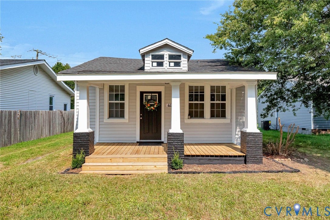 403 Masonic Lane, Masonic, Henrico, VA 23223 Light-colored siding exterior with a dark-paneled entry door, a covered porch with wooden decking, and white columns with dark brick bases