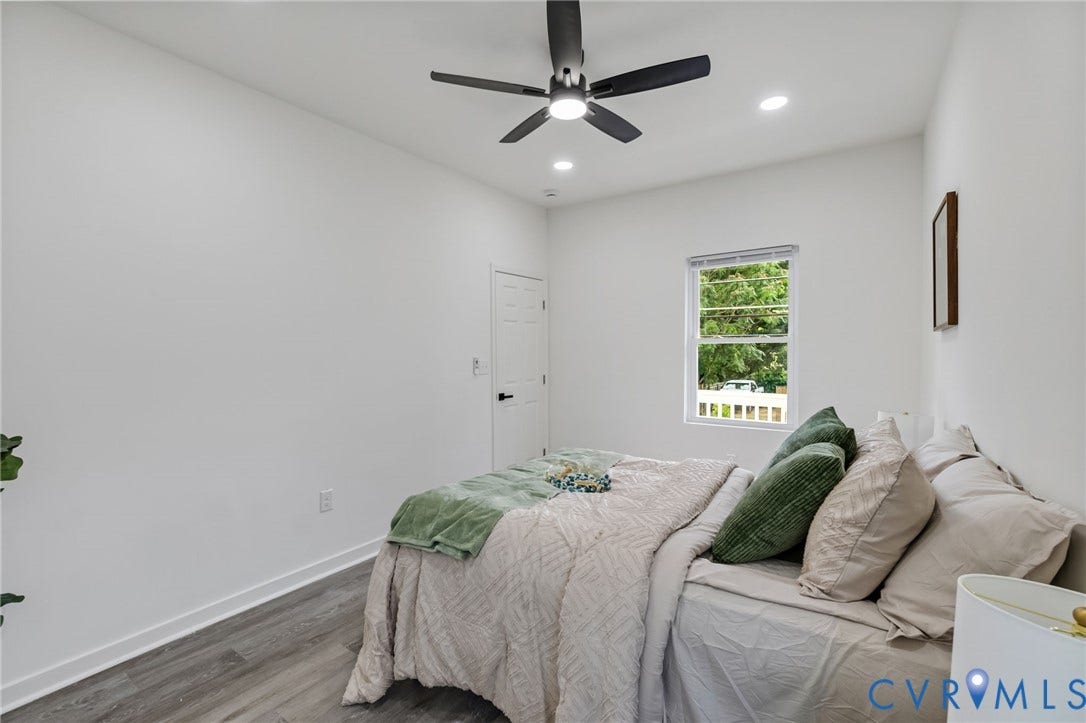 409 S Jefferson Street, Bolling, Petersburg, VA 23803 Bright secondary bedroom with wood-finish flooring, ceiling fan with integrated lighting, large window with natural light, and clean white walls throughout