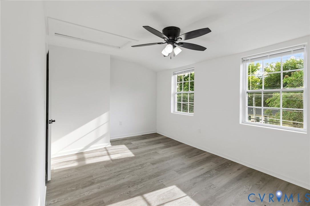 409 S Jefferson Street, Bolling, Petersburg, VA 23803 Wood-finish flooring, white walls, black ceiling fan with integrated lighting, two windows with white trim