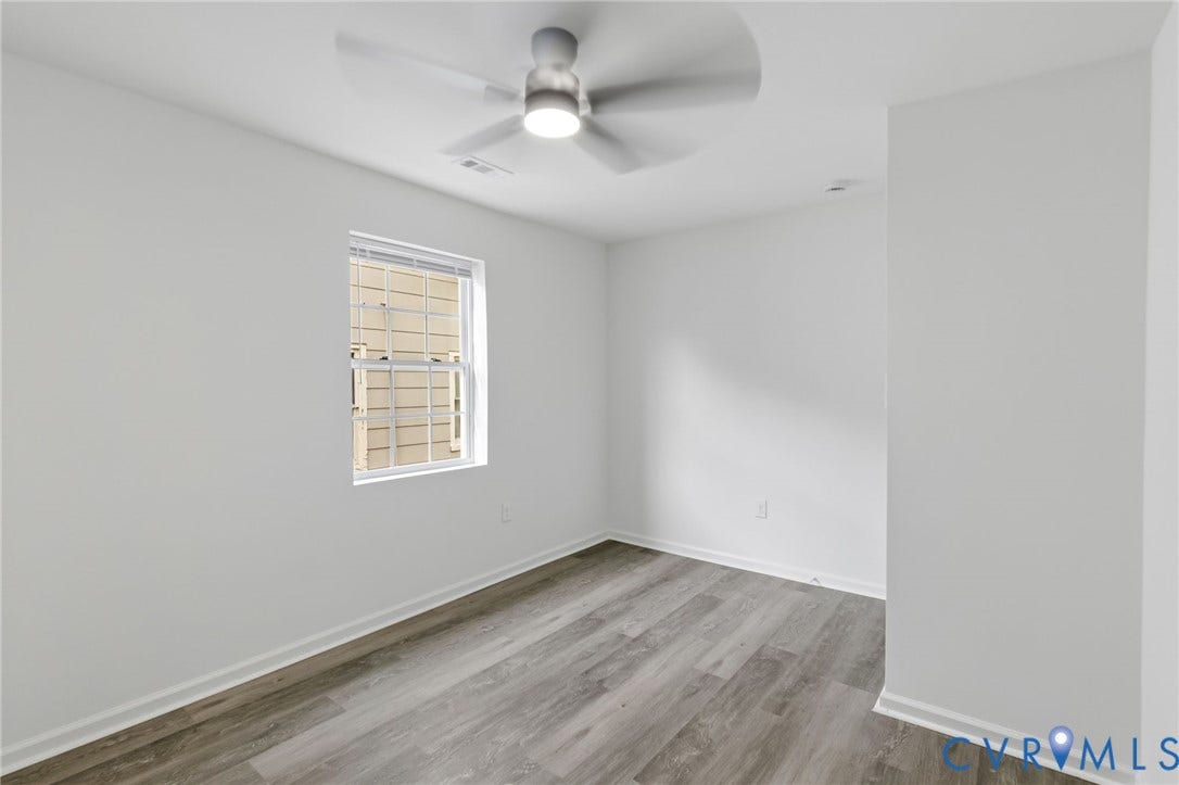 409 S Jefferson Street, Bolling, Petersburg, VA 23803 Bright bedroom with hardwood-finish flooring, neutral walls, and abundant natural light from a single-hung window