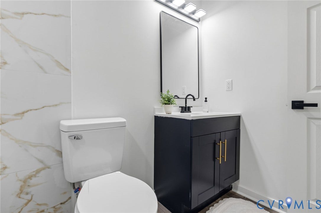 409 S Jefferson Street, Bolling, Petersburg, VA 23803 Modern bathroom featuring a black vanity with dual hardware handles, white ceramic vessel sink, and a polished quartz countertop