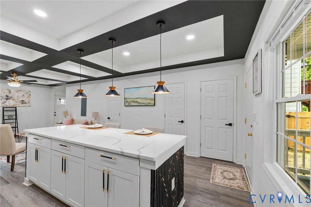 409 S Jefferson Street, Bolling, Petersburg, VA 23803 Kitchen island featuring a white countertop with gray veining, white cabinetry with gold-tone hardware, and a black and white patterned base