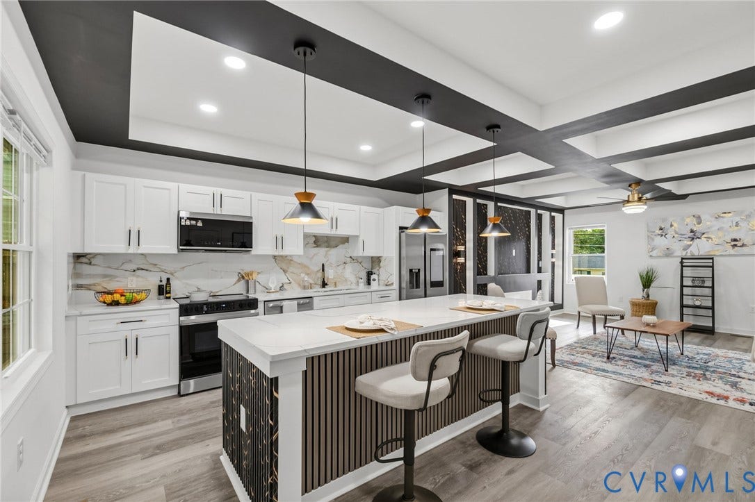 409 S Jefferson Street, Bolling, Petersburg, VA 23803 Contemporary kitchen and open living area featuring white cabinetry with hardware accents, stainless steel appliances, and a large waterfall-edge island with fluted detailing