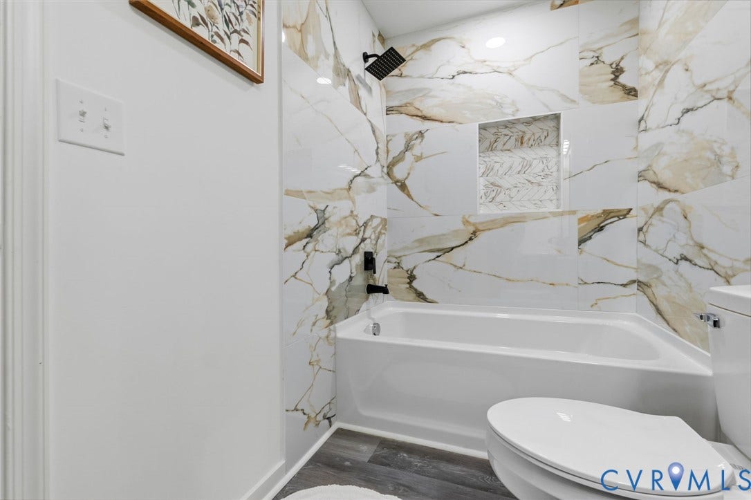 409 S Jefferson Street, Bolling, Petersburg, VA 23803 Modern bathroom featuring elegant marble-look tile wall surround with warm veining, white subway tile flooring, and a sleek white porcelain toilet