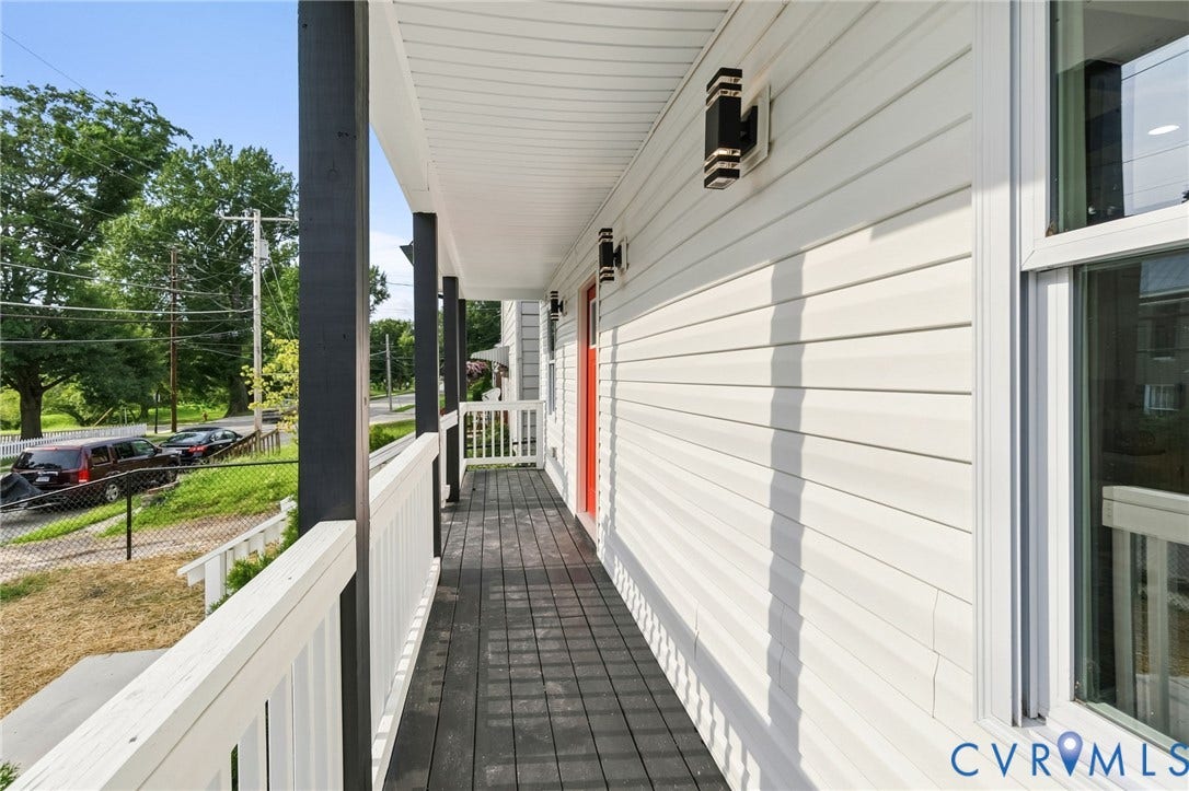 409 S Jefferson Street, Bolling, Petersburg, VA 23803 Porch featuring dark wood-finish flooring, white railing, dark support posts, and modern exterior lighting fixtures