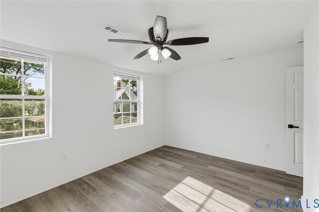 409 S Jefferson Street, Bolling, Petersburg, VA 23803 Two windows with white frames, wood-finish flooring, white walls, and a ceiling fan with light fixture