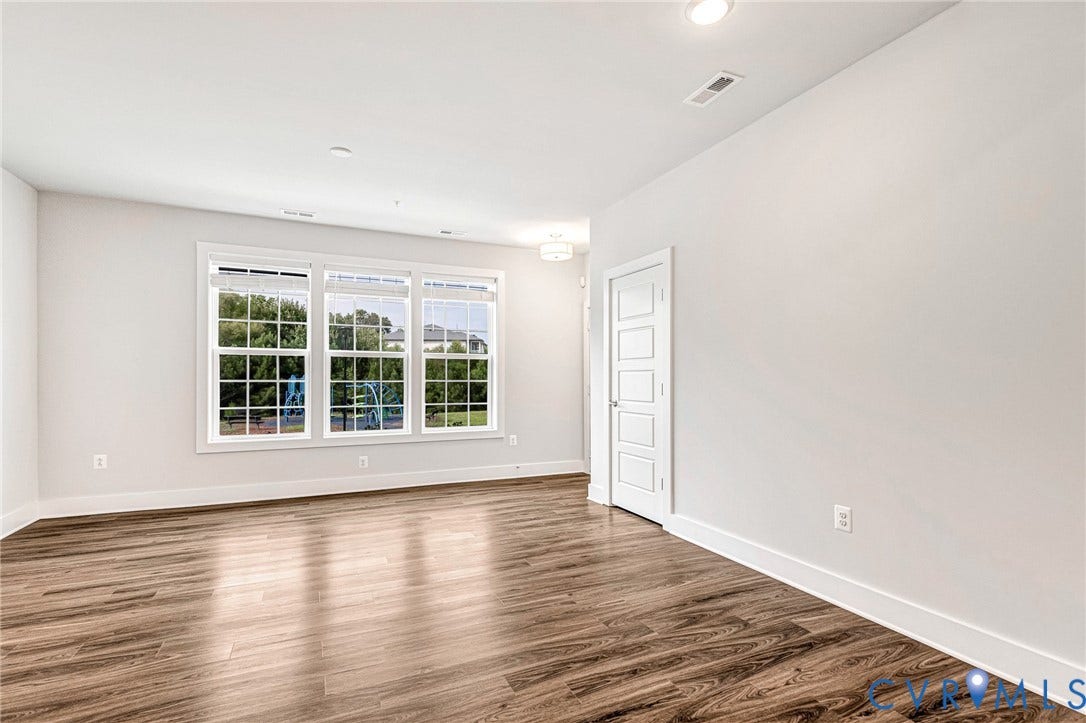 4347 Saunders Station Loop, #A, Glen Allen, VA 23233 Bright, light-filled room showcasing gleaming wood-finish flooring, triple casement windows with multiple panes, crisp white walls, recessed ceiling lighting, and white six-panel doors with polished hardware