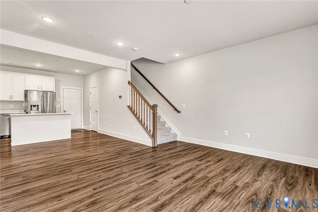 4347 Saunders Station Loop, #A, Glen Allen, VA 23233 Open-concept living area featuring warm wood-finish flooring, recessed ceiling lighting, and a modern staircase with wooden handrail