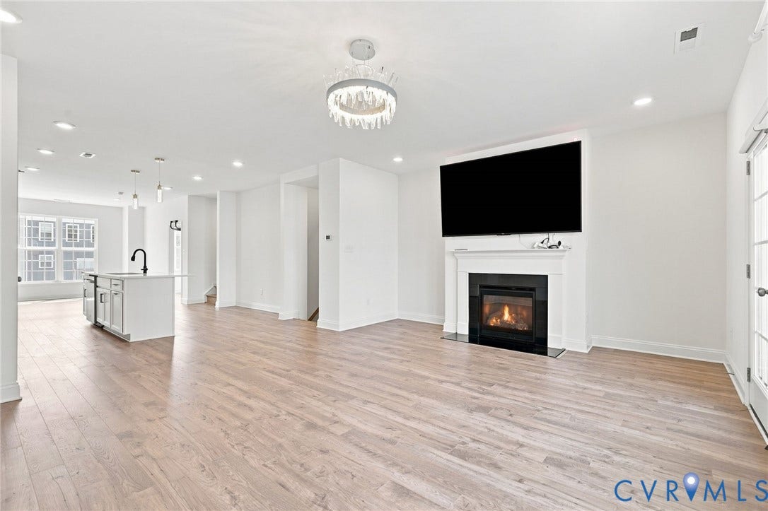 13820 Village View Drive, Midlothian, VA 23114 Expansive space featuring wood-finish flooring, a fireplace with a white mantel, and a kitchen island with pendant lighting