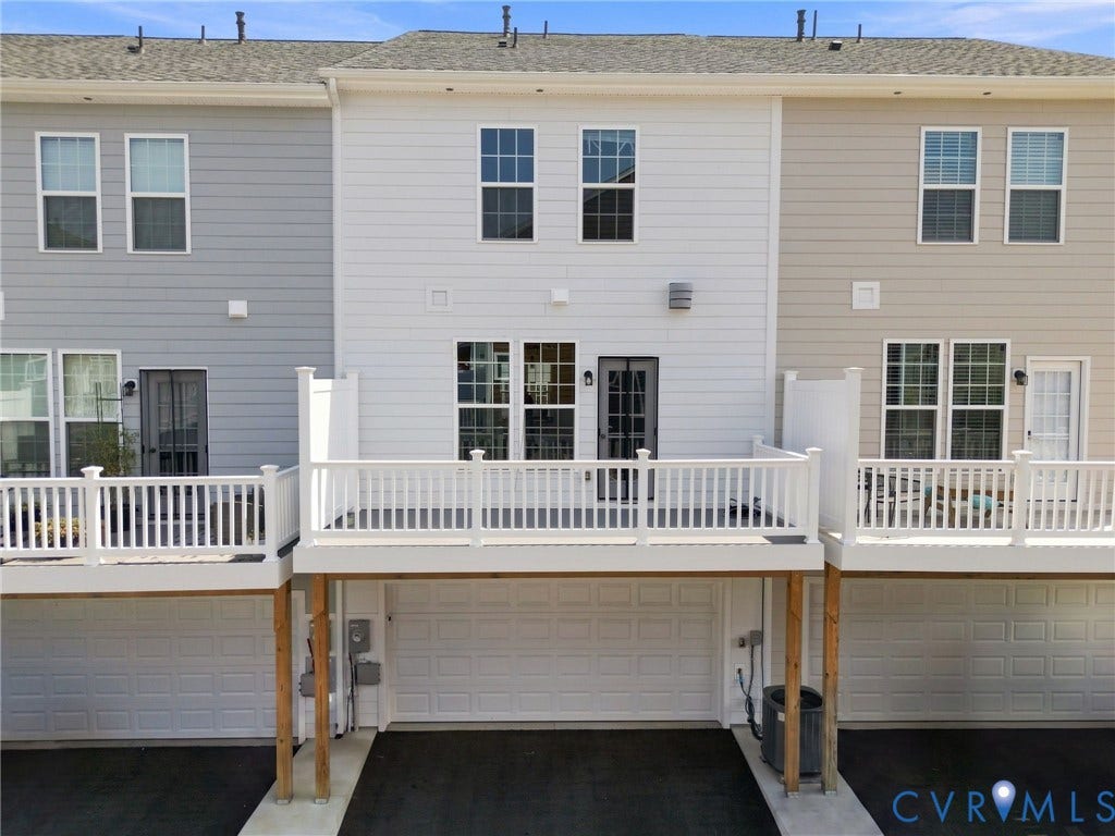 13820 Village View Drive, Midlothian, VA 23114 Multi-level townhome featuring a rear deck with white railings, a ground-level garage, and a light-colored siding exterior