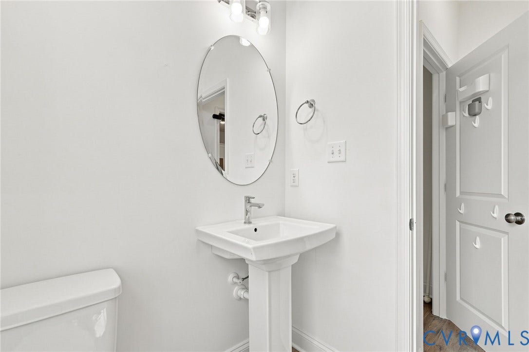 13820 Village View Drive, Midlothian, VA 23114 Pedestal sink with chrome faucet, oval mirror, and wall-mounted light fixture