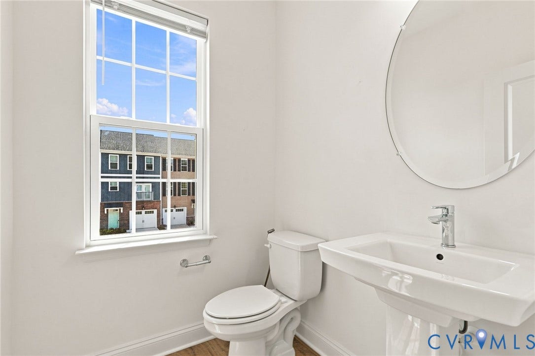 13820 Village View Drive, Midlothian, VA 23114 Pedestal sink with chrome faucet, oval frameless mirror, and a double-hung window