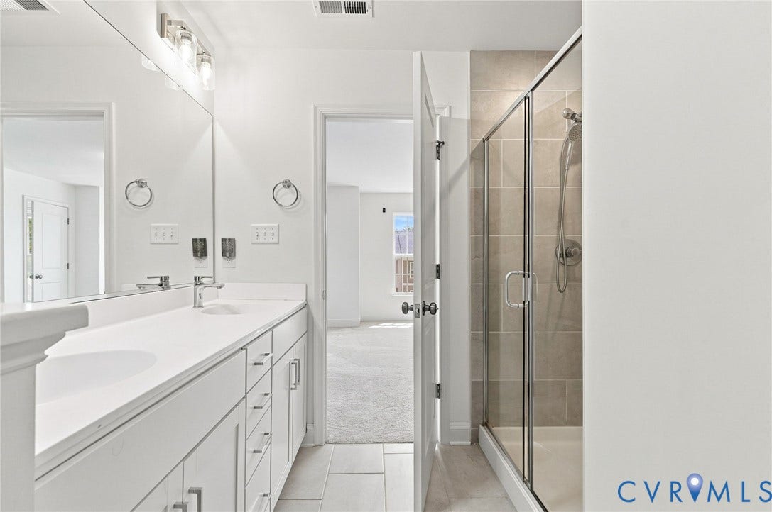 13820 Village View Drive, Midlothian, VA 23114 Dual vanity with integrated sinks, brushed nickel fixtures, contemporary lighting, and a glass-enclosed shower featuring tile surround