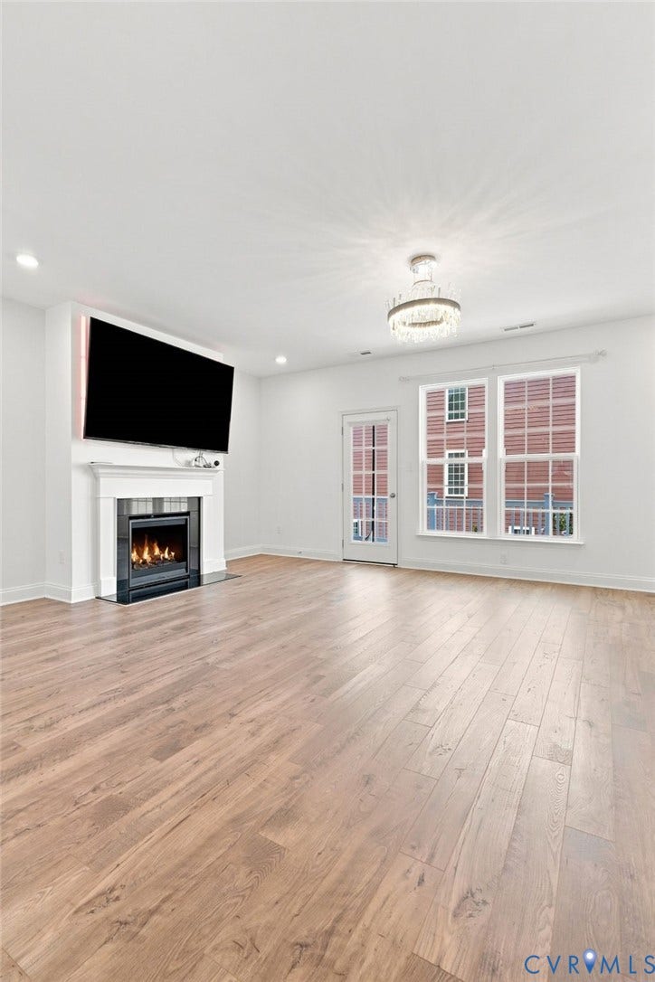 13820 Village View Drive, Midlothian, VA 23114 Spacious living area featuring wood-finish flooring, a fireplace with a white mantel, and a multi-pane window